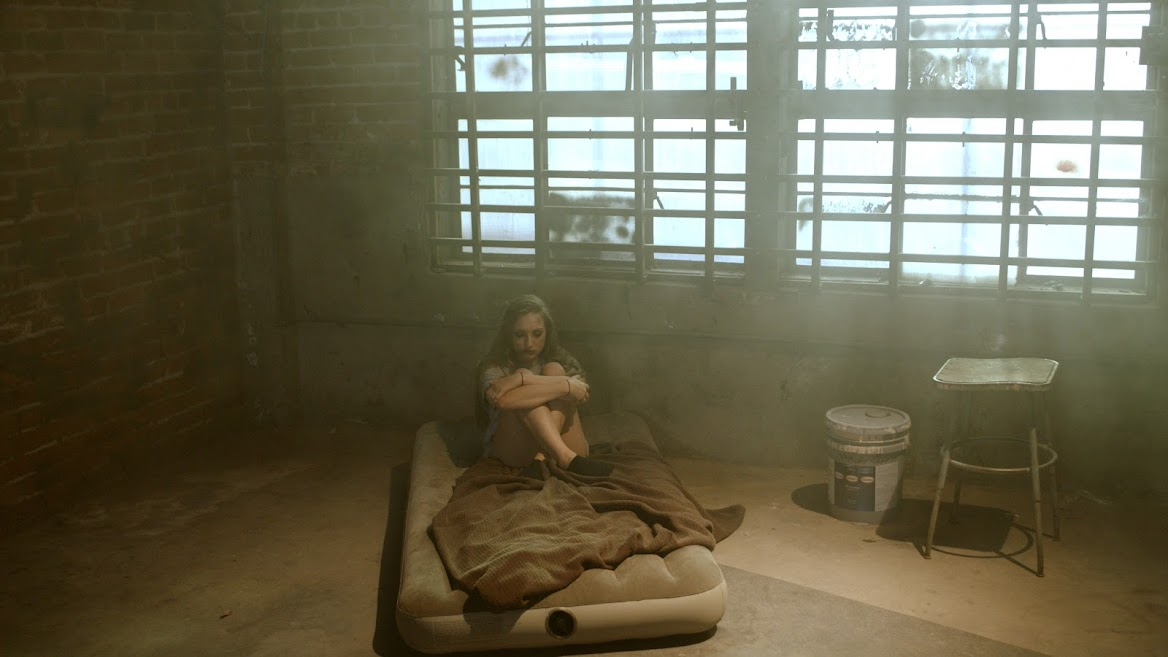 Alt Text: A marketing video snapshot of video storytellers with a girl sitting on a mattress.